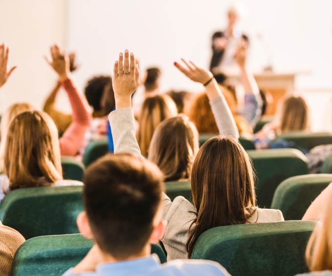 People in meeting room raising hands